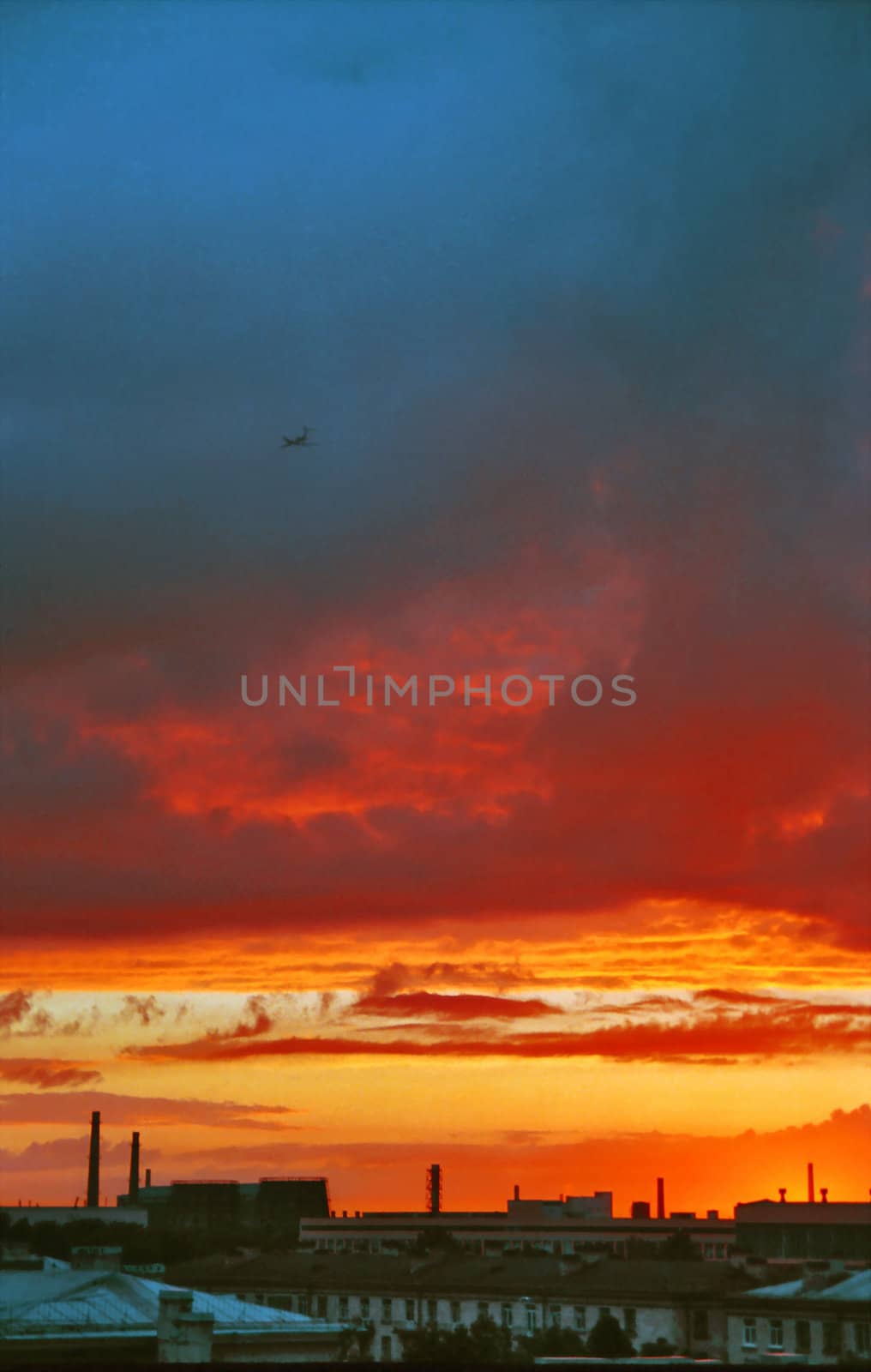 Industrial evening landscape with landing airplane