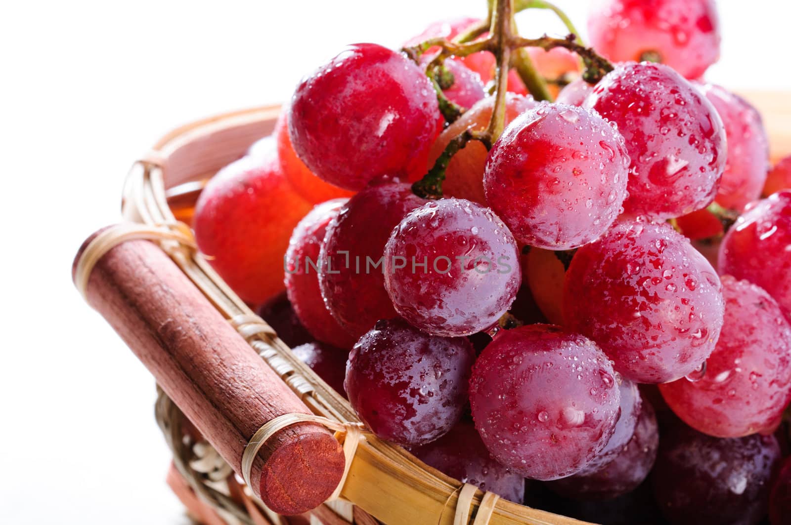 Bunch of red grapes in a basket on a white background.