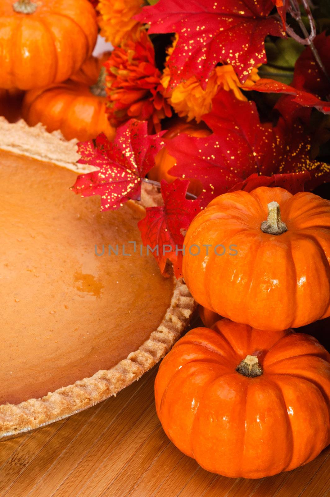 Pumpkin pie in a pie plate with autumn leaves and pumpkins.