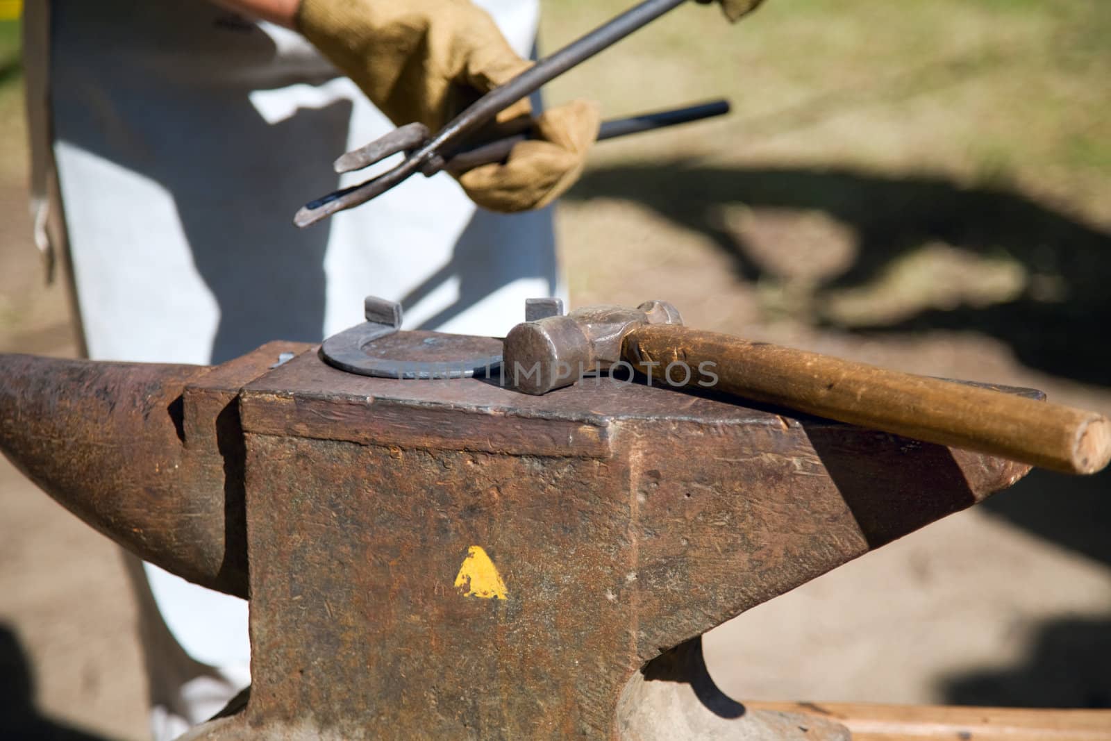 hands of blacksmith by working metal with hammer and anvil. Hammering glowing steel - to strike while the iron is hot.