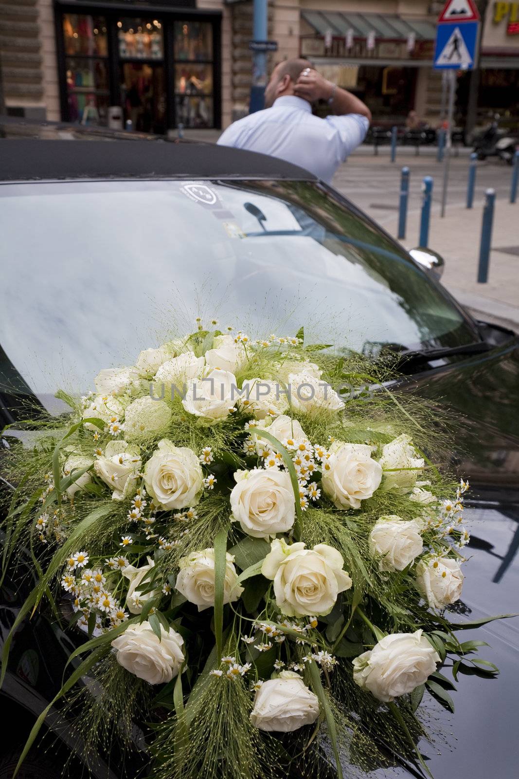 Decorated limousine and driver waiting for the bride in city.