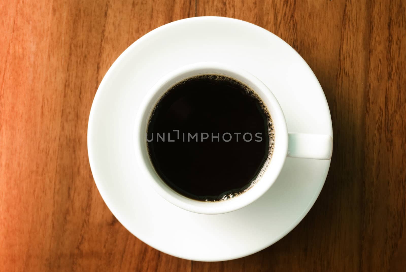 Hot coffee cup on wooden table in top view.