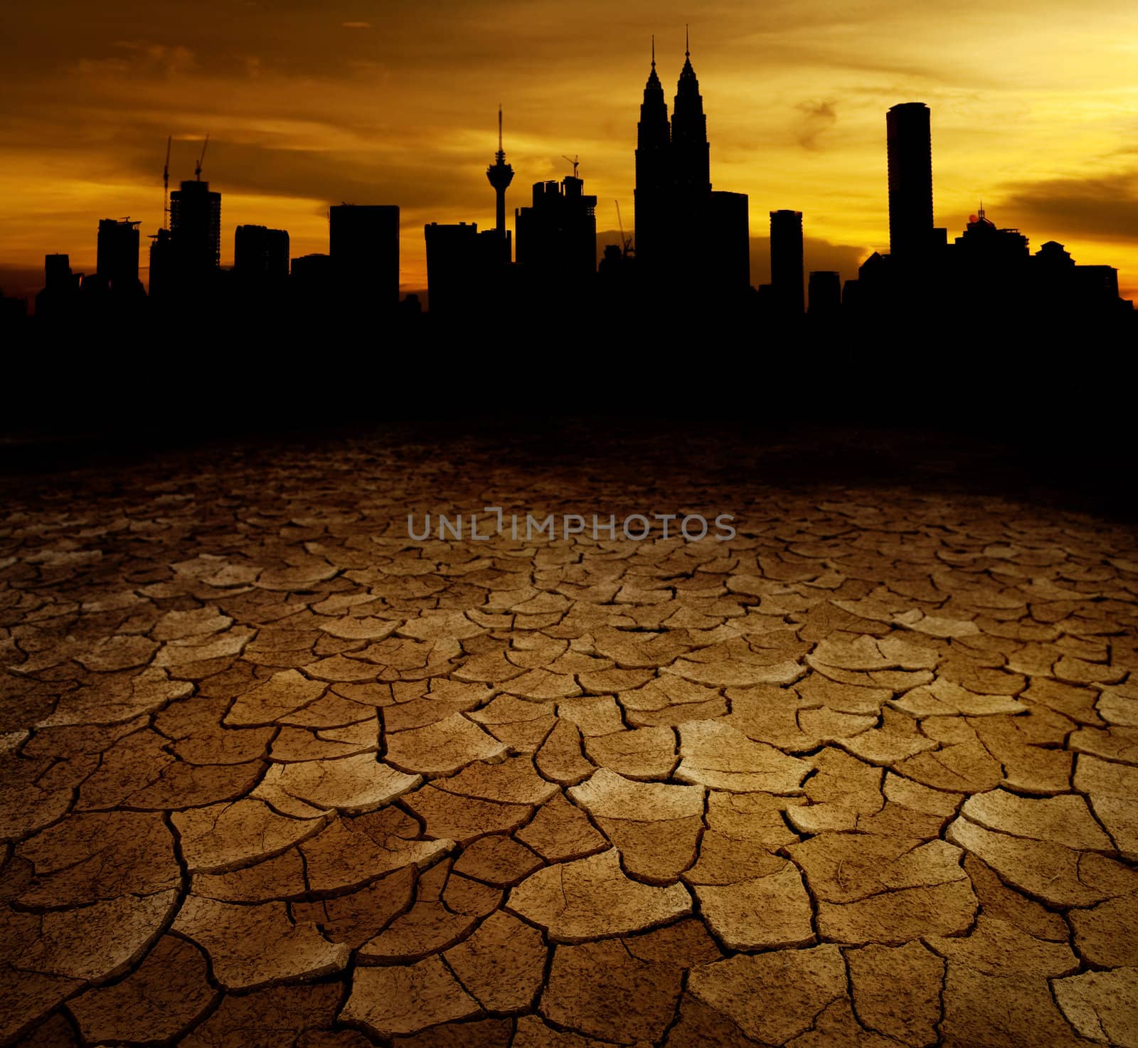 A city looks over a desolate cracked earth landscape in sunset