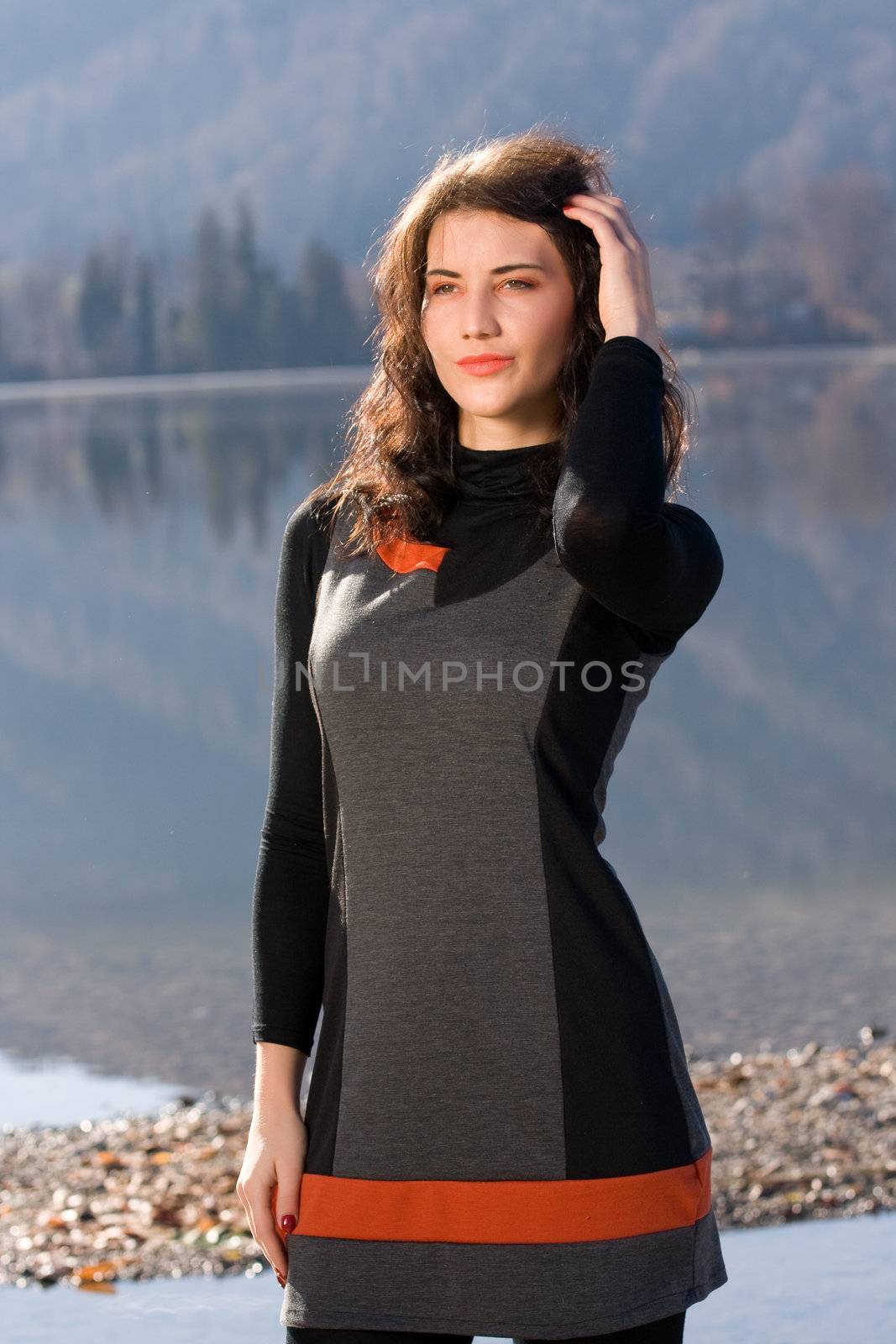 Pensive woman in dress on the lakeshore