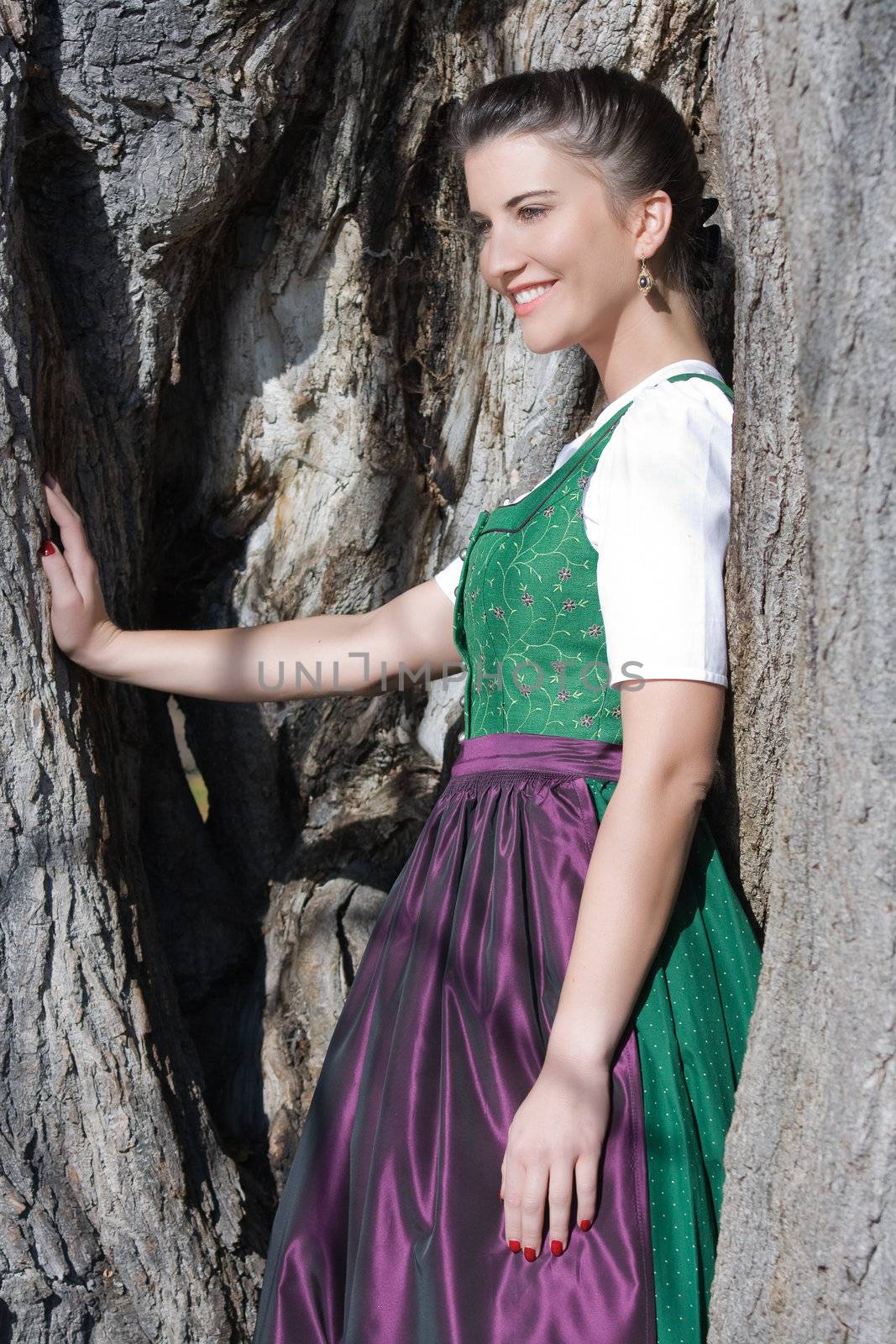 Bavarian woman in costume stands in a tree