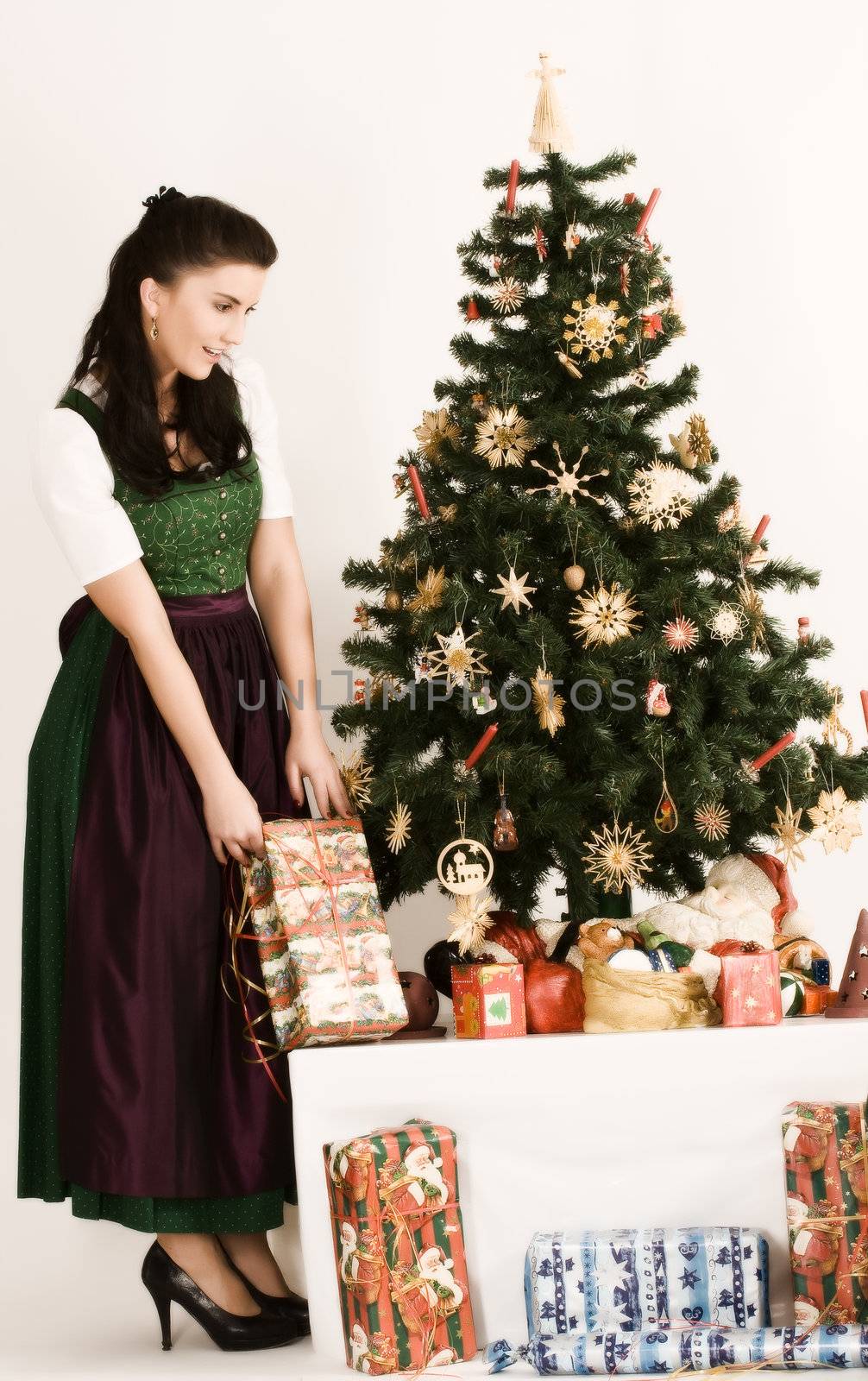 Bavarian girl with Christmas parcels before a table with Christmas gifts