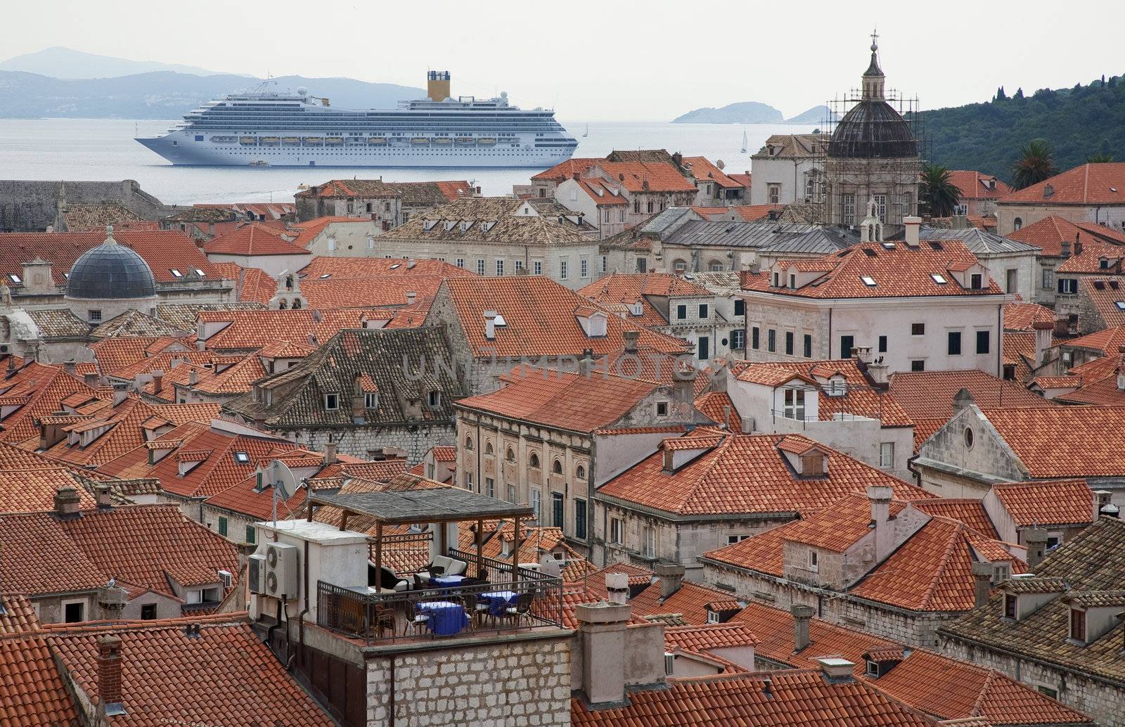 The roofs of Dubrovnik, Croatia seen from the town wall. A cruiser at the Adriatic Sea outside the town is sailing tourists by shuttle boats to and from the town.