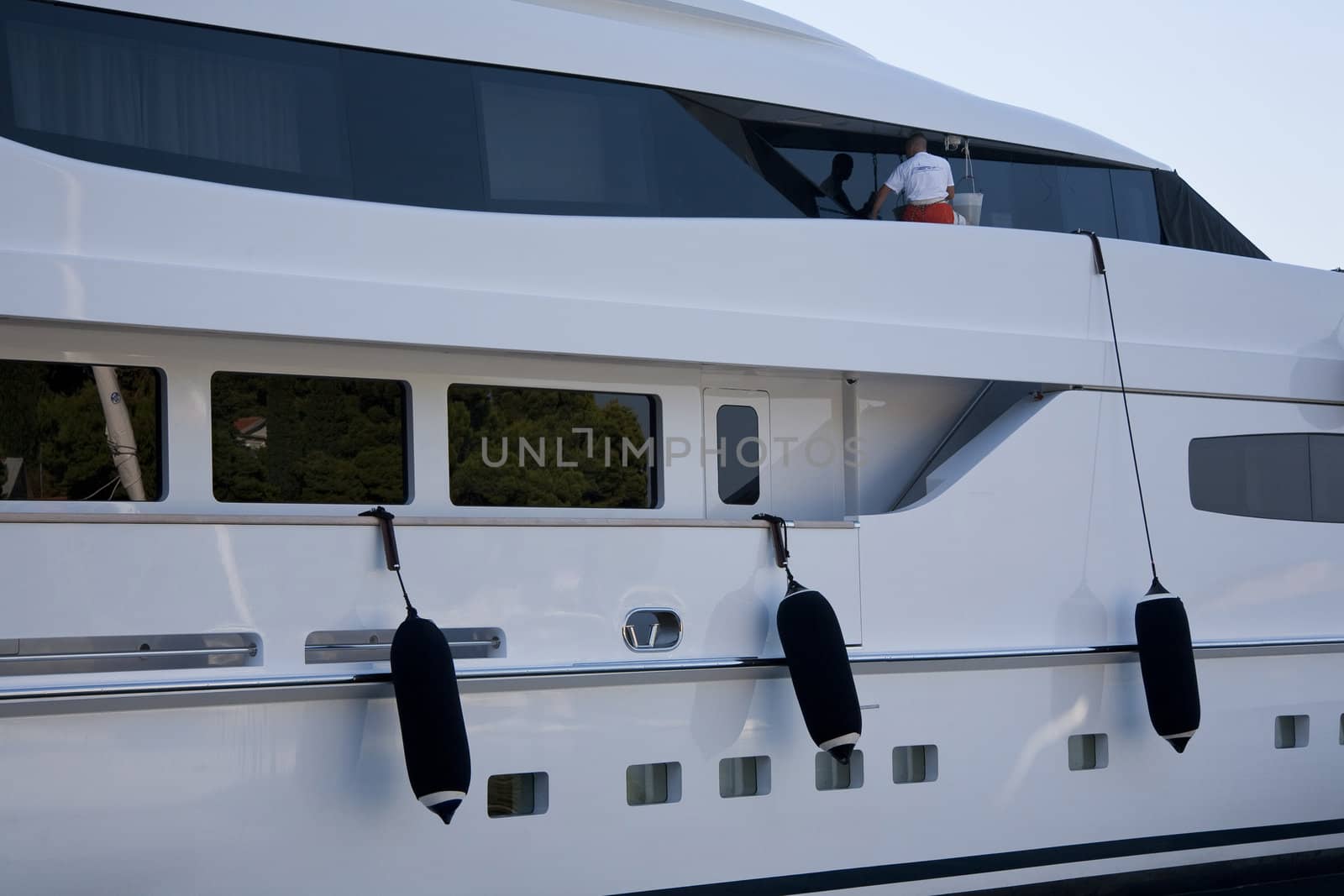 Man cleaning windows on a 37 million Euro yacht in the marina of Cavtat, Croatia.