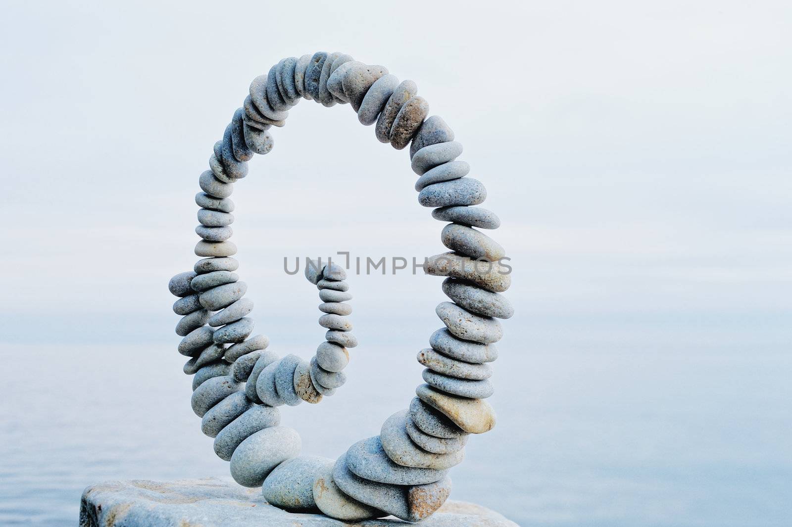 White spiral of pebbles on the boulder at the sea