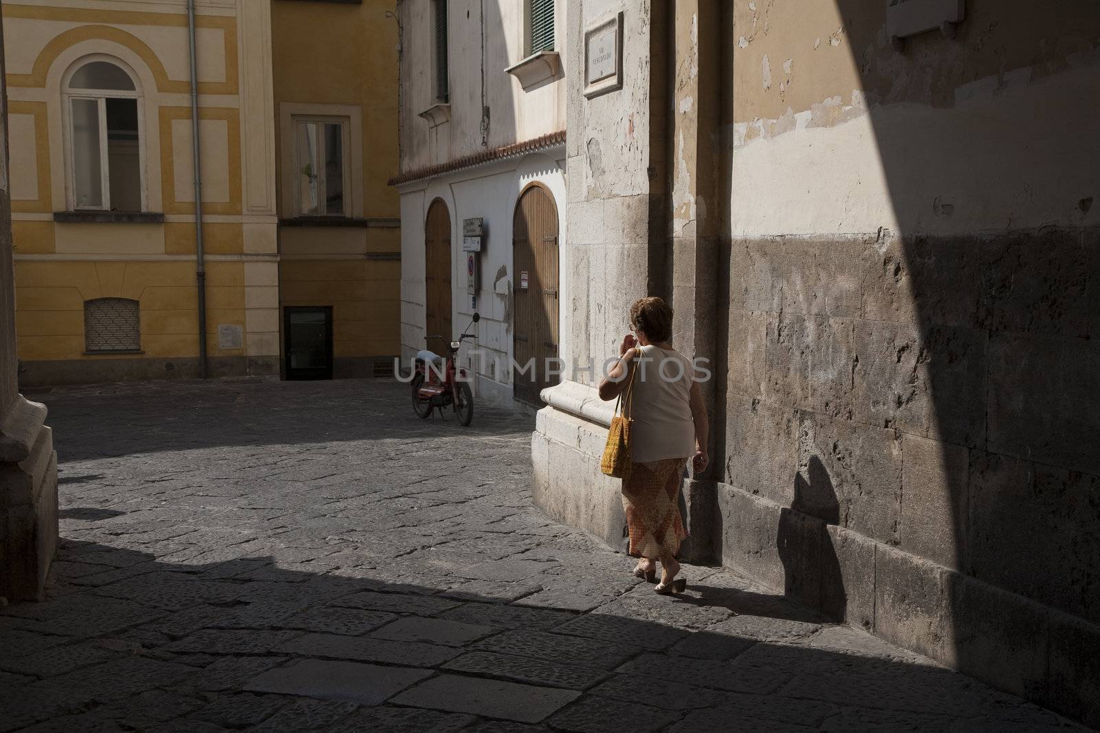 Senior Italian lady walking in the sun on a hot September day.