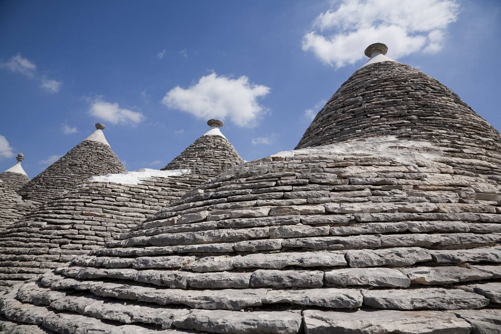 Closeup of trulli roofs against a blue sky. Alberobello, Apulia - Italy. A trullo is a traditional Apulian stone dwelling with a conical roof. The style of construction is specific to Itria Valley.