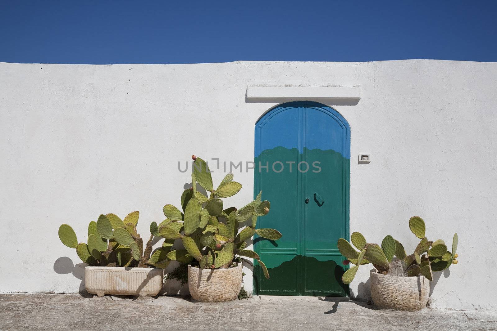 Nice painted door and wall in the Apulian town Ostuni, Italy on a hot September day with a nice blue sky.