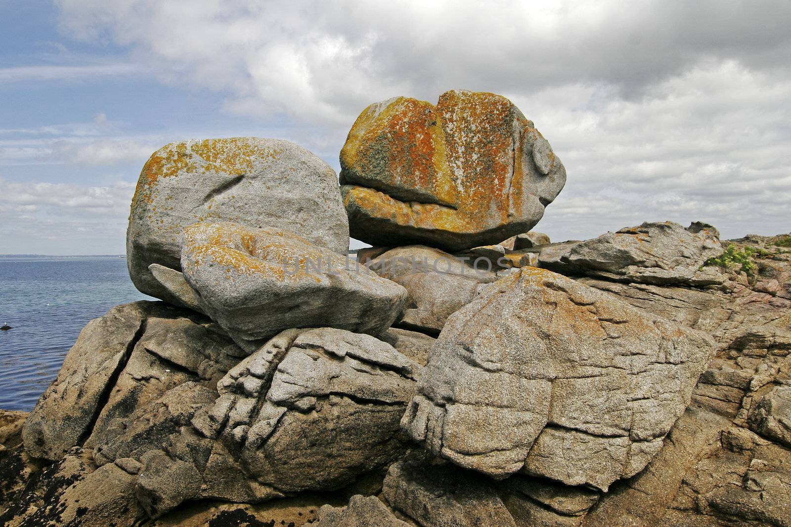 Big Stone on the rock coast near Pointe de Trevignon, Brittany, North France. Stone with orange lichens.