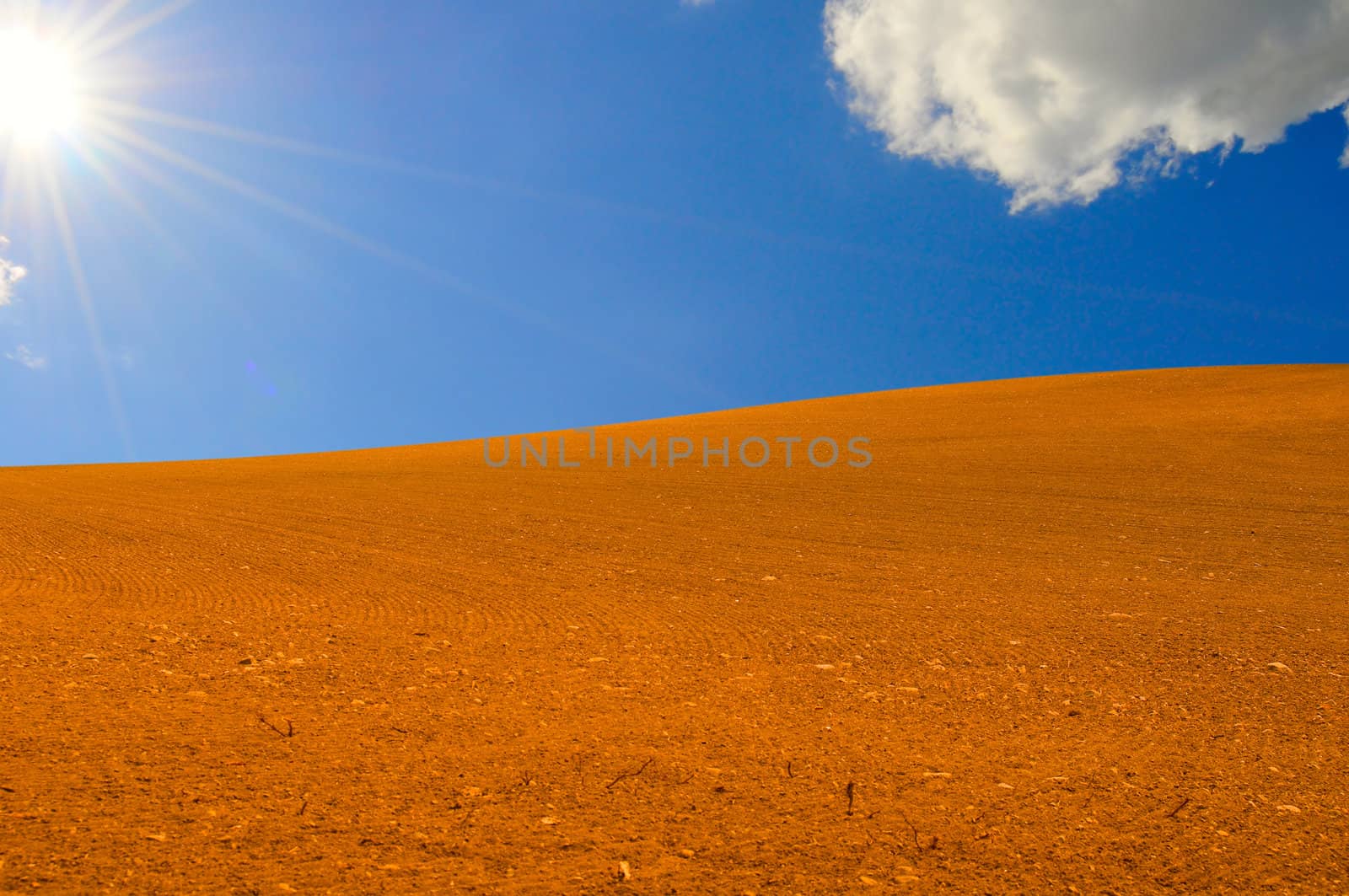 Red sand and clear blue sky with white clouds