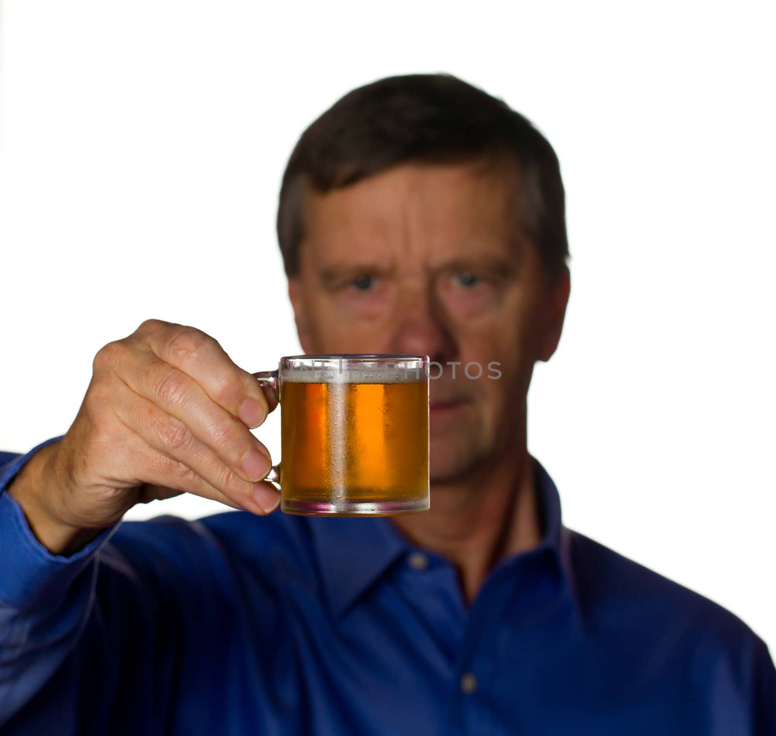 Senior retired male with a cool glass of beer in a very small tankard with the man out of focus