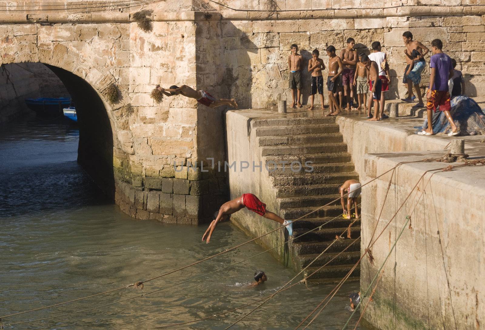 Group of boys diving into the harbour in the fishing village of Essaouira, Morocco.