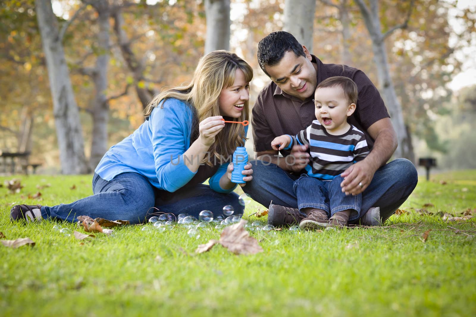 Happy Young Mixed Race Ethnic Family Playing with Bubbles In The Park.