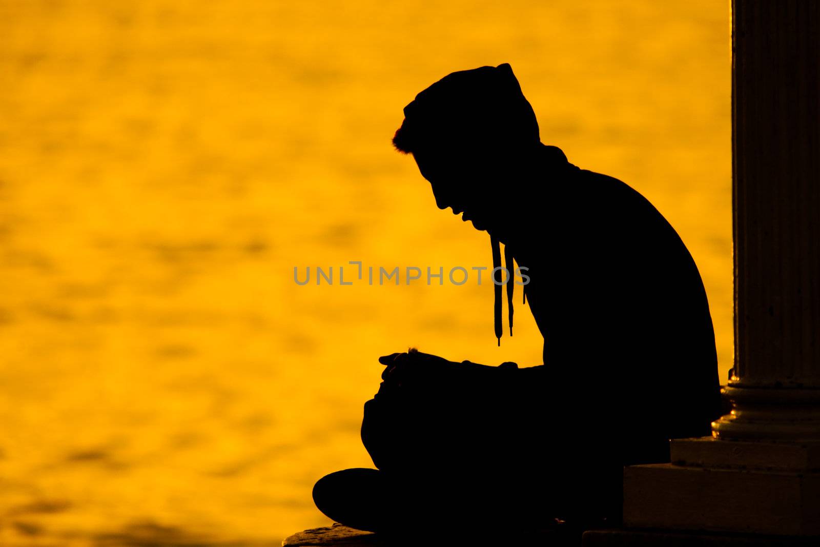 A silhouette figure of a young man sitting