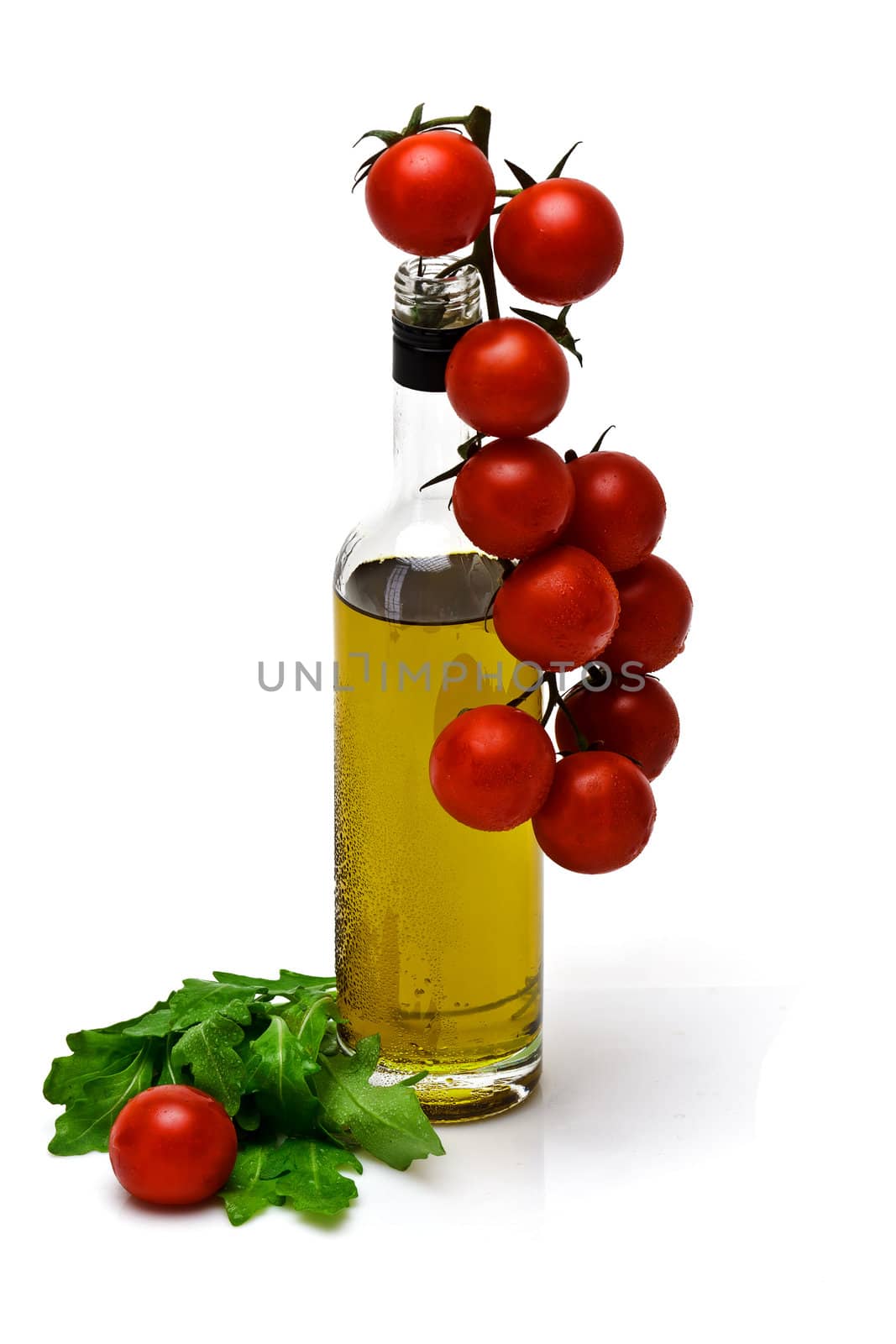 bottle of olive oil with cherry and arugula on white background