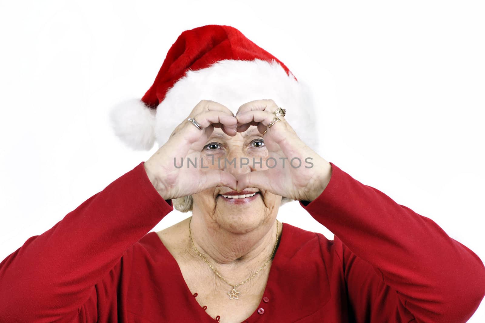 Grandmother sending her love for Christmas by making a heart shape with her hands while wearing Santa Claus hat.