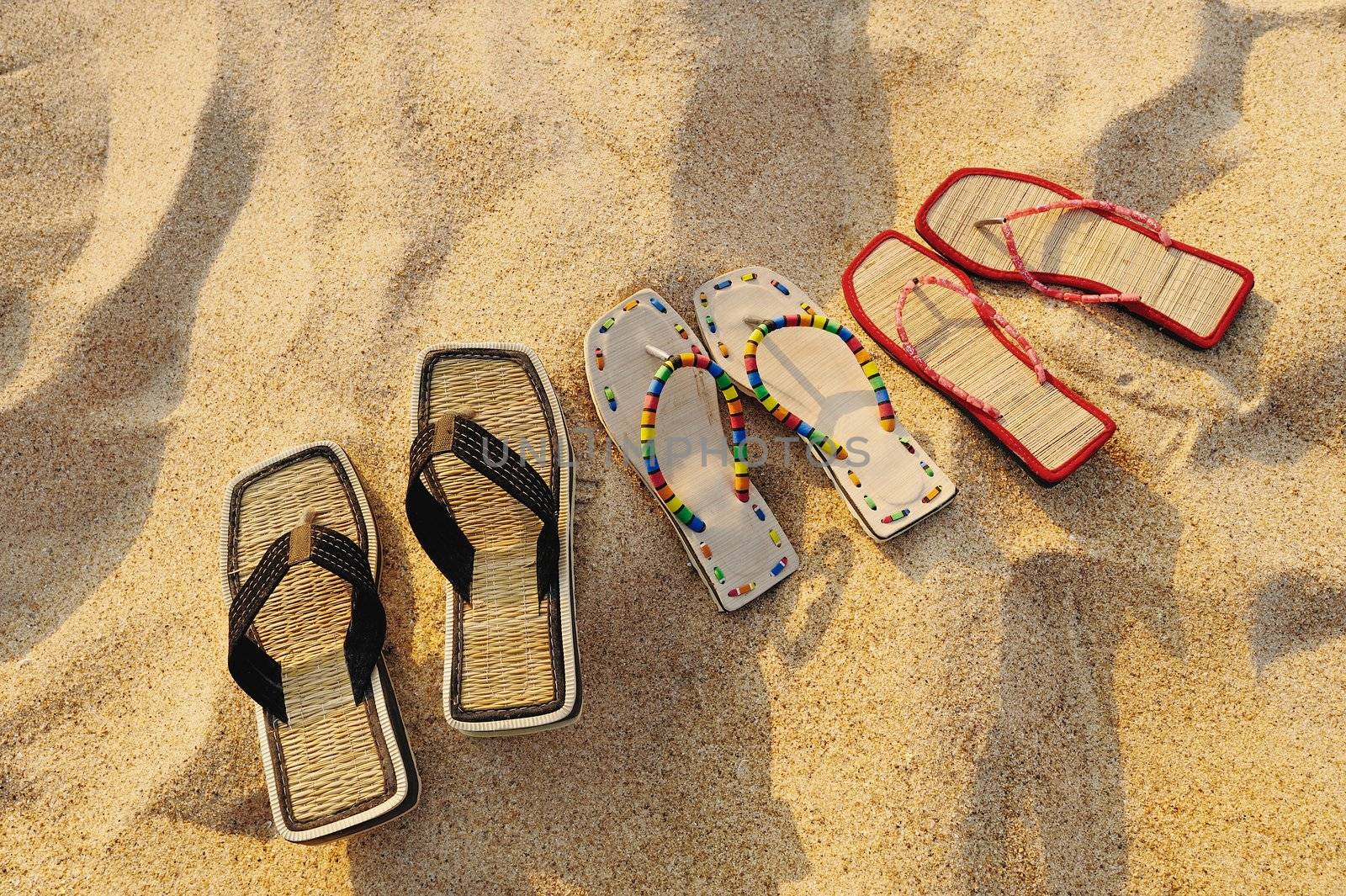 Three pair of beach sandals on the sandy beach