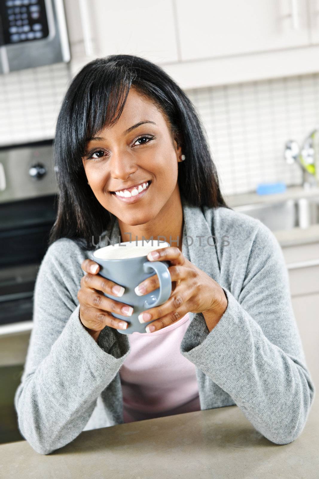 Woman in kitchen with coffee cup by elenathewise