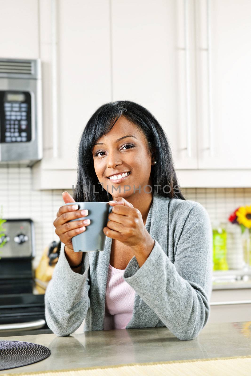 Woman in kitchen with coffee cup by elenathewise