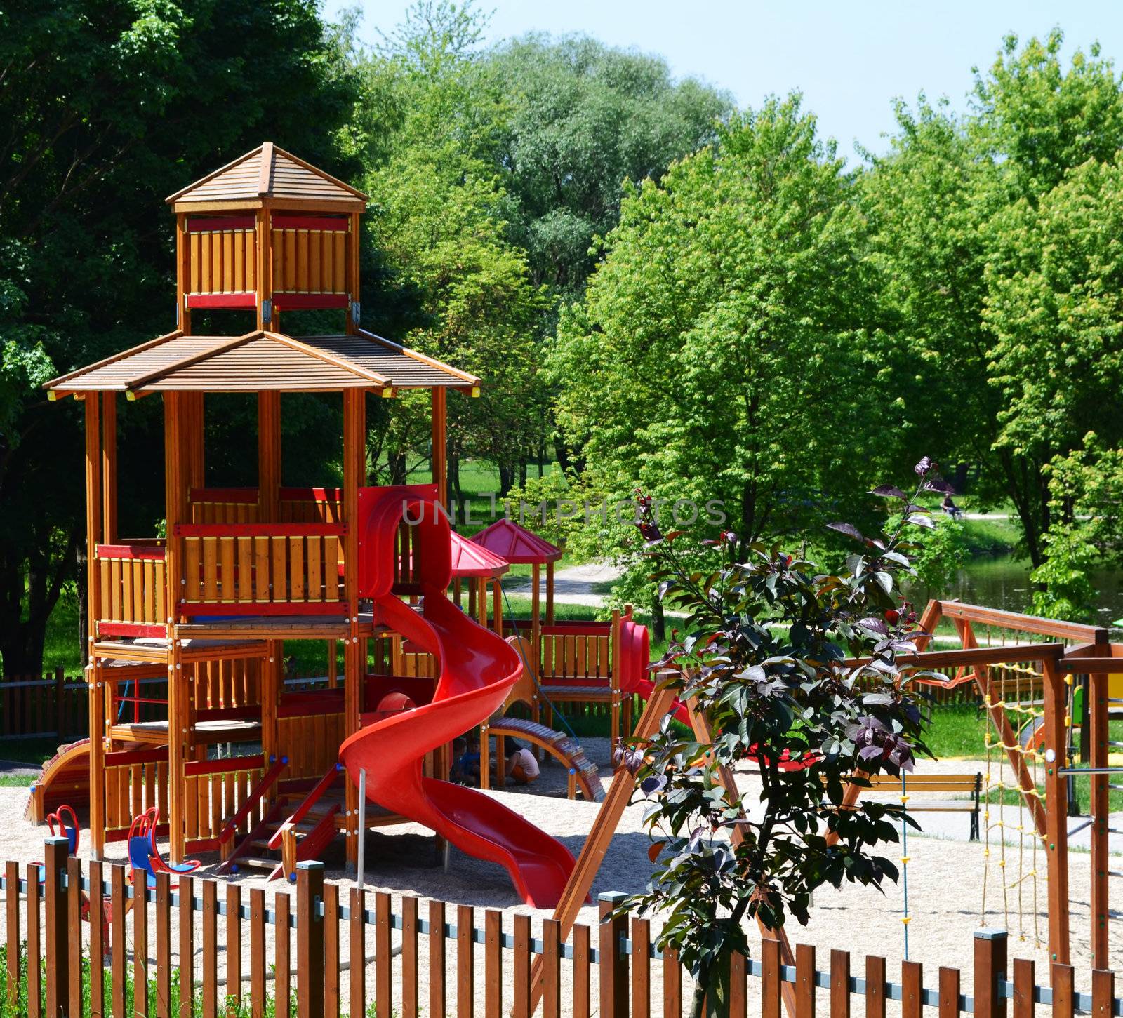 Wooden castle with slide on a modern playground, situated in a leisure park. The park is on the edge of a town and, with its woody, green, natural surroundings and various facilities, ensures relaxation and recreation for the town's inhabitants and visitors, including kids and children.