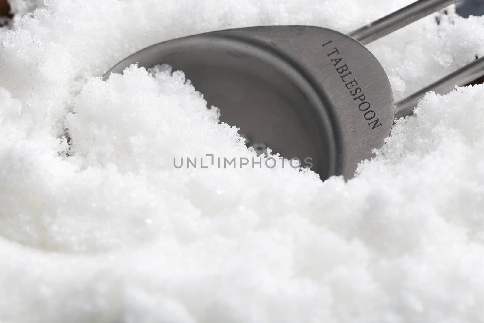 Close-up of teaspoon in sugar granules.