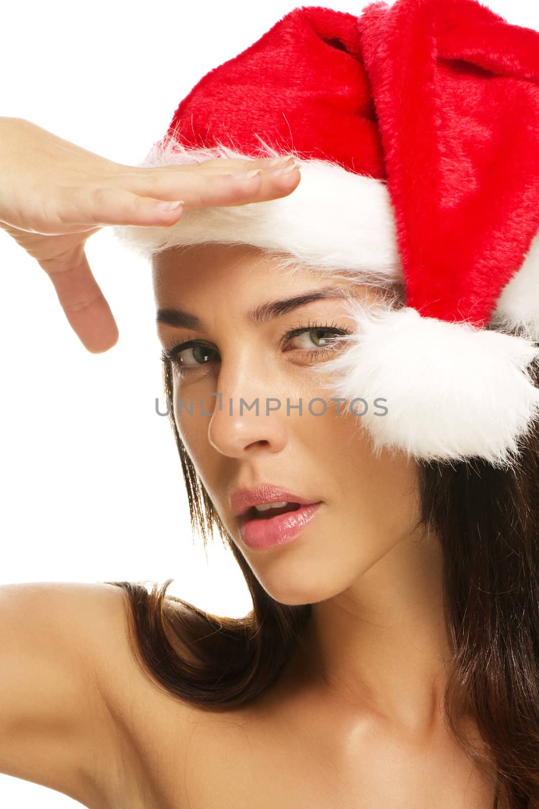 young woman wearing santas hat shields her sight on white background