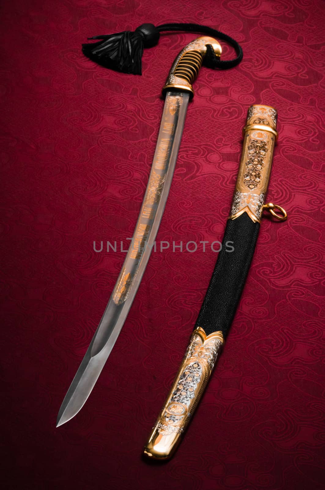 Ornated and old sword laying on red, flat background