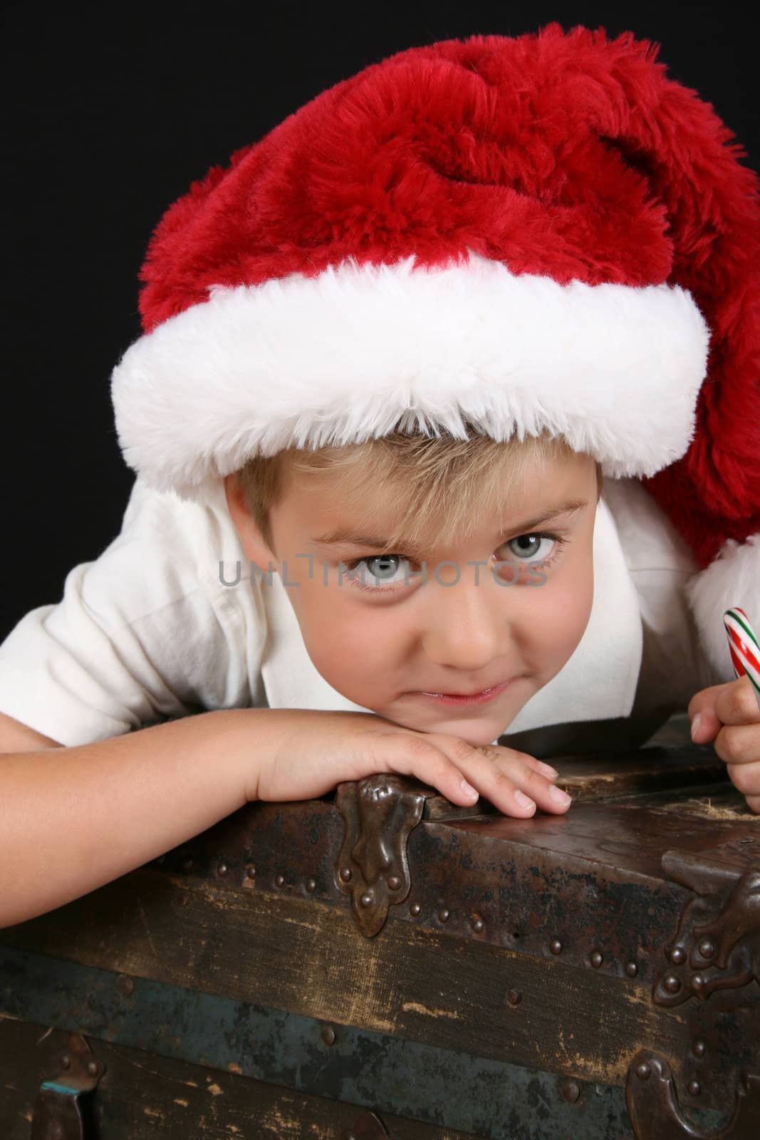 Cute young boy lying on an antique trunk wearing a christmas hat
