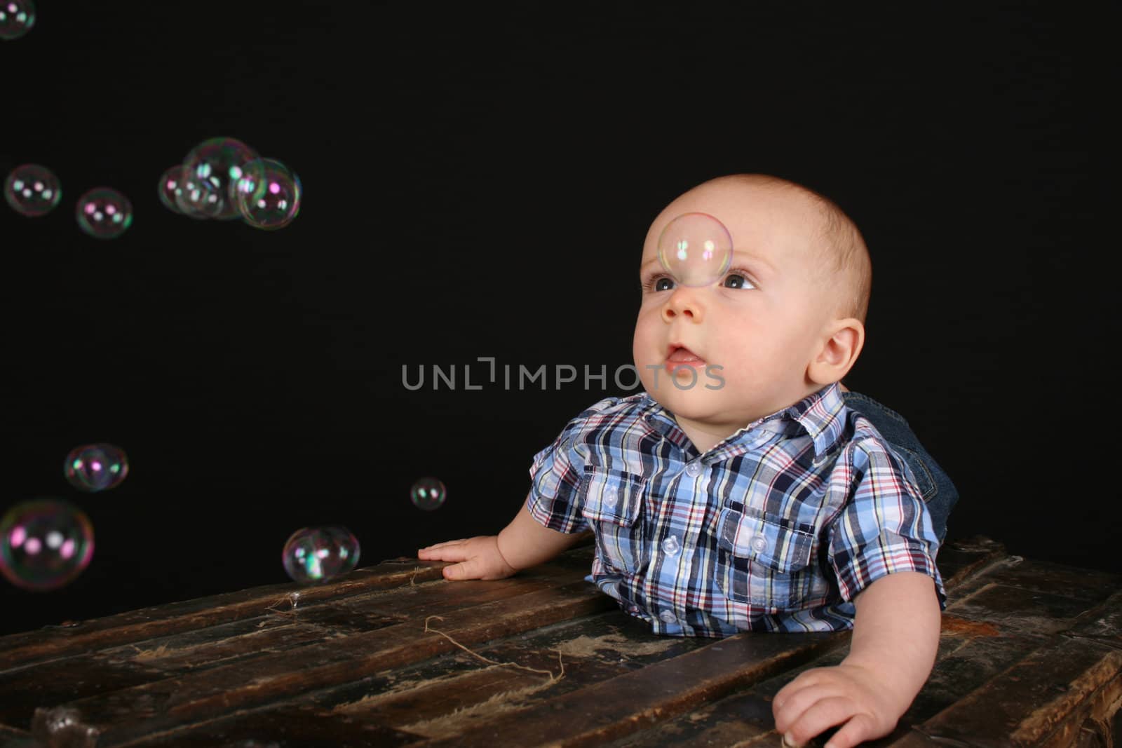 Cute little boy on an antique trunk wearing blue jeans 