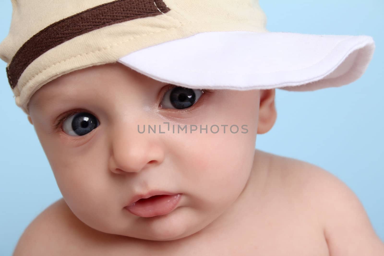 Cute baby boy wearing a brown hat against blue background