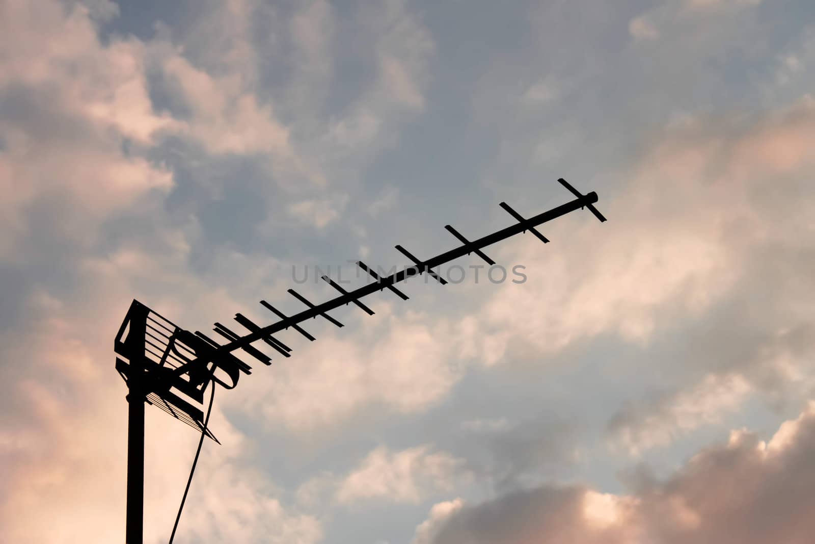 Home television antenna on the background of white and reddish evening clouds