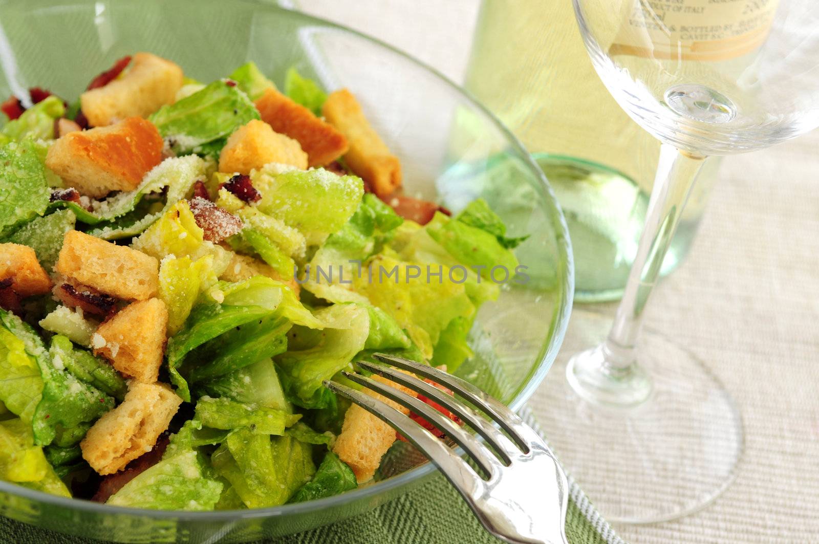 Caesar salad served in a glass bowl and white wine