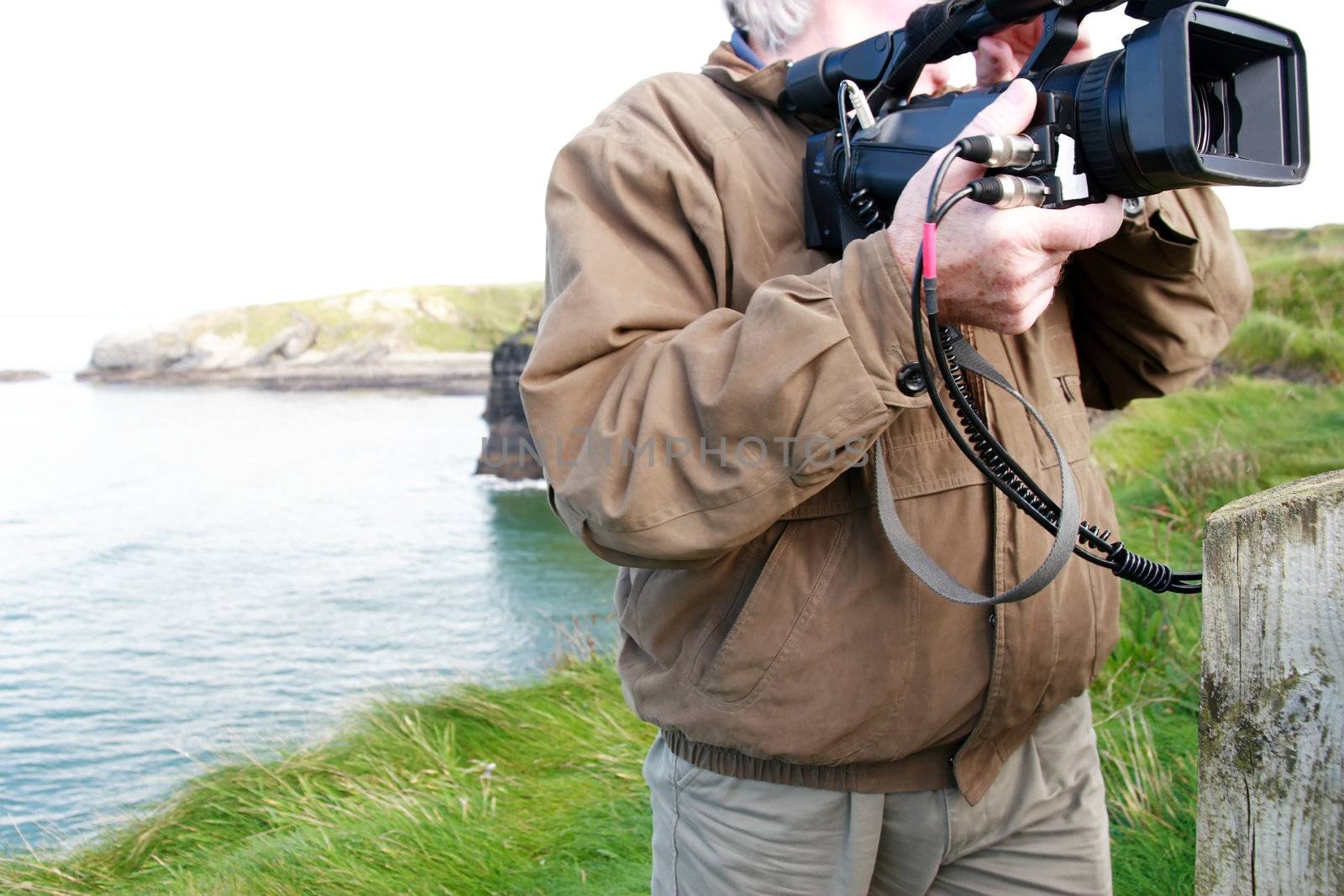 a cameraman filming on the cliff edge in ballybunion ireland