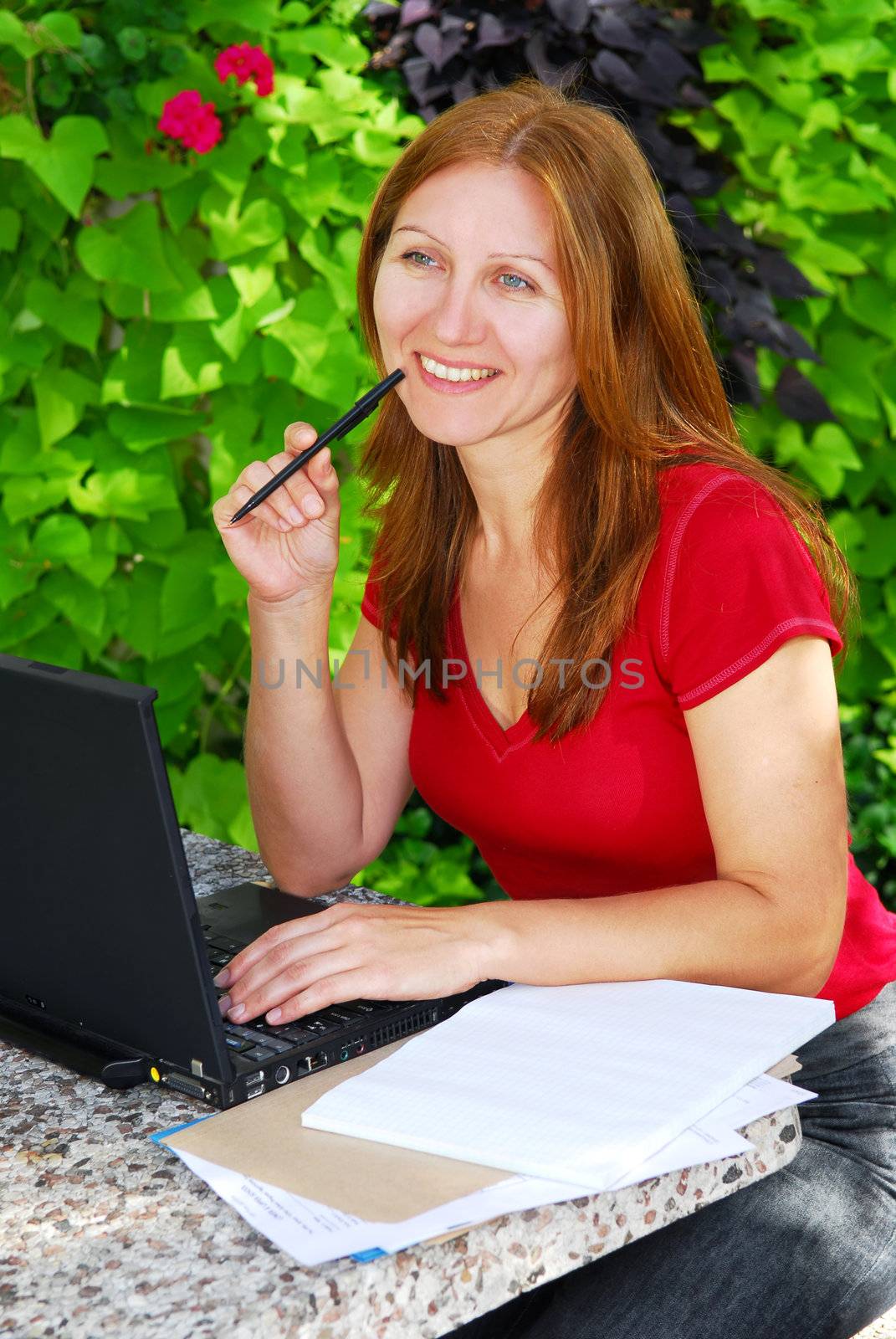 Happy mature woman working on a portable computer in her garden