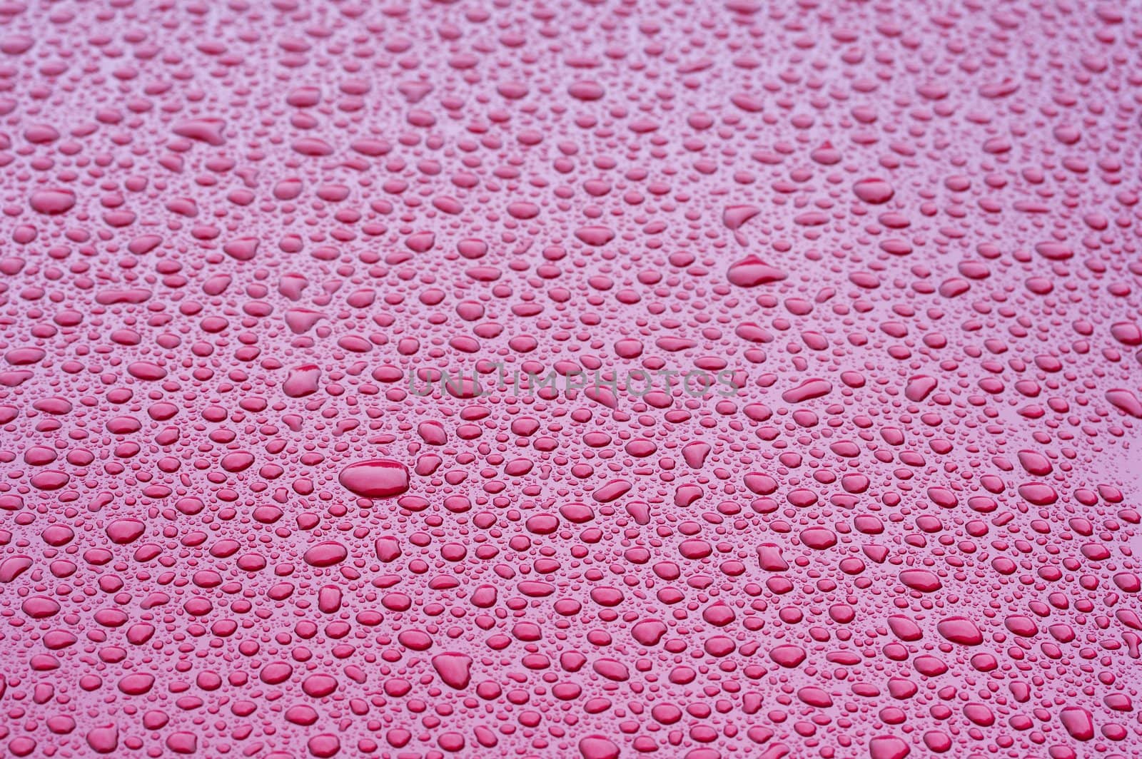 a picture of water drops on a red metal surface