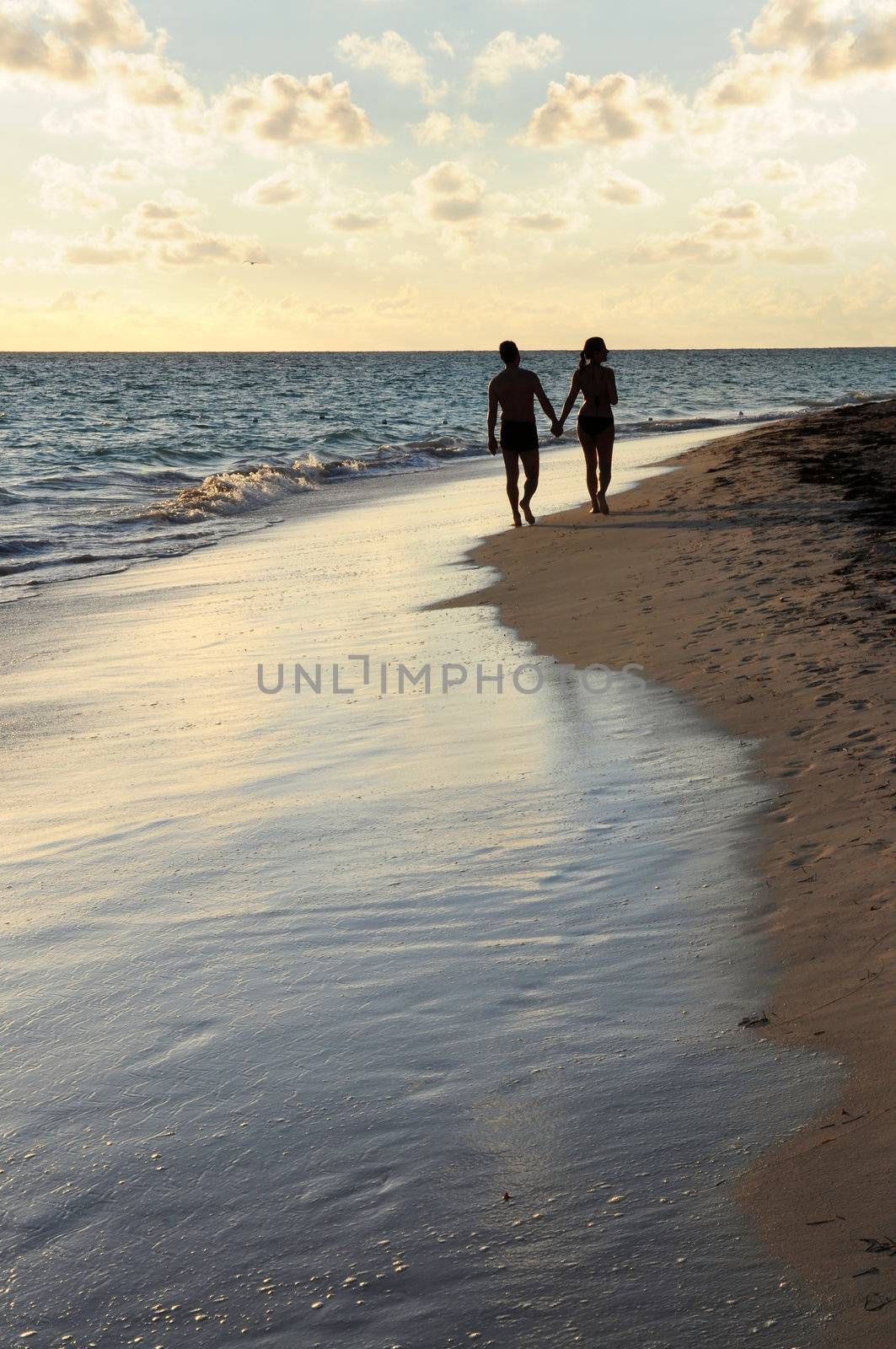 Couple taking a walk on a sandy beach of tropical resort