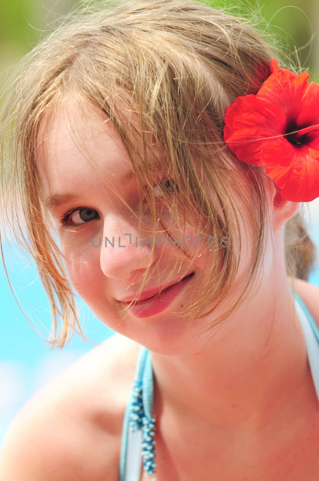 Portrait of a young girl on tropical beach with red flower