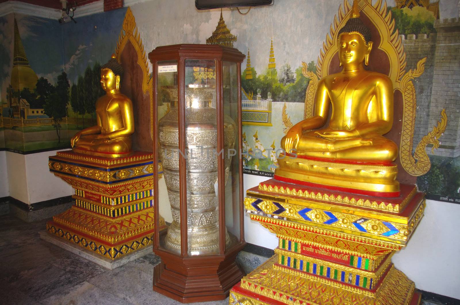 Dans un hall du temple de Wat Phrathat Doi Suthep à Chiang Mai au nord-ouest de la Thaïlande , des bouddhas et des jarres en argent fermées dans des chasses vitrées .
Les milliers de fidèles qui viennent journellement visiter le temple , laissent des sommes importantes d’argent . Le temple est extrêmement  riche au popint que d’autres temples moins fréquentés de la région déposent des urnes pour profiter de cette manne financière .