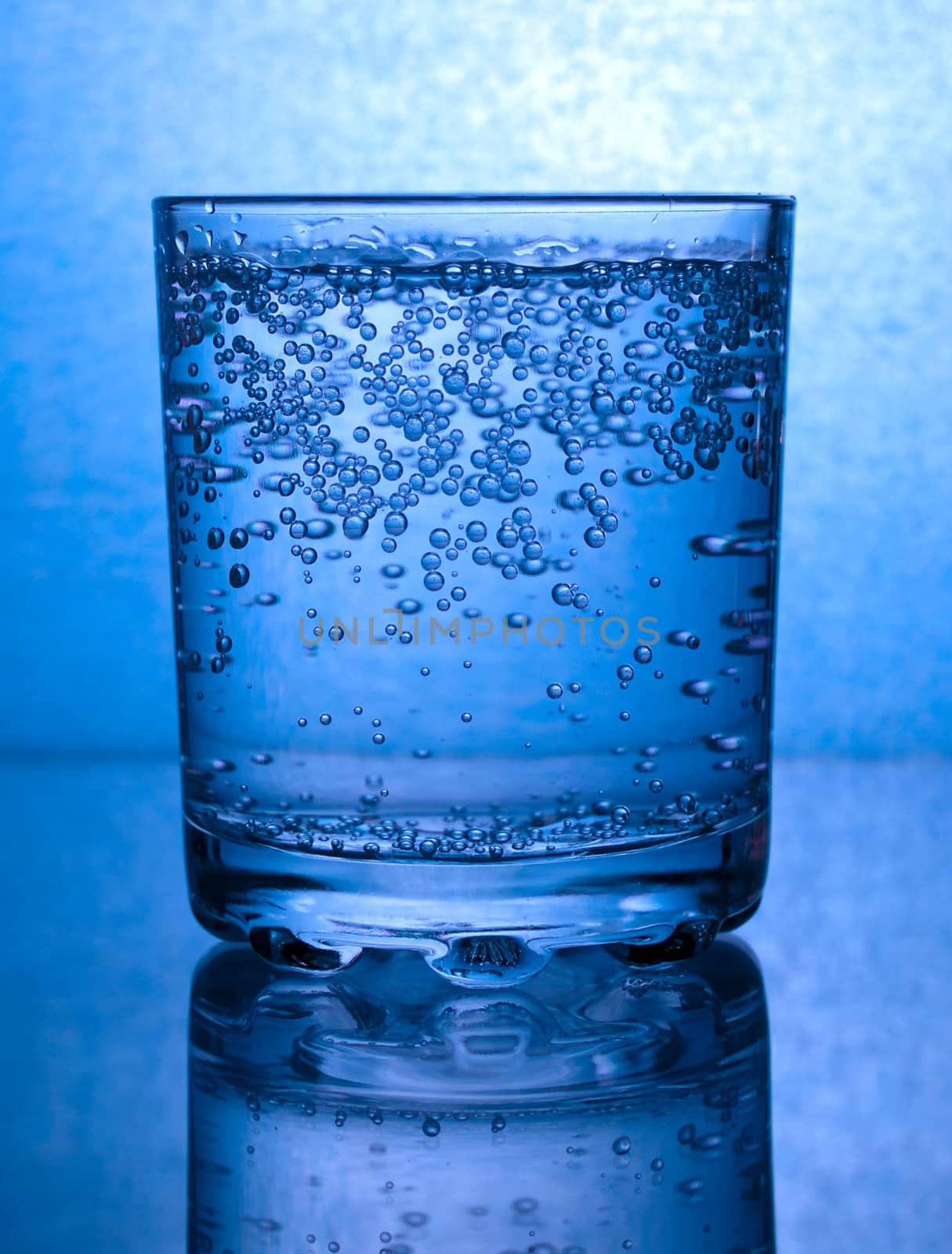 Glass of water with bubbles, in blue