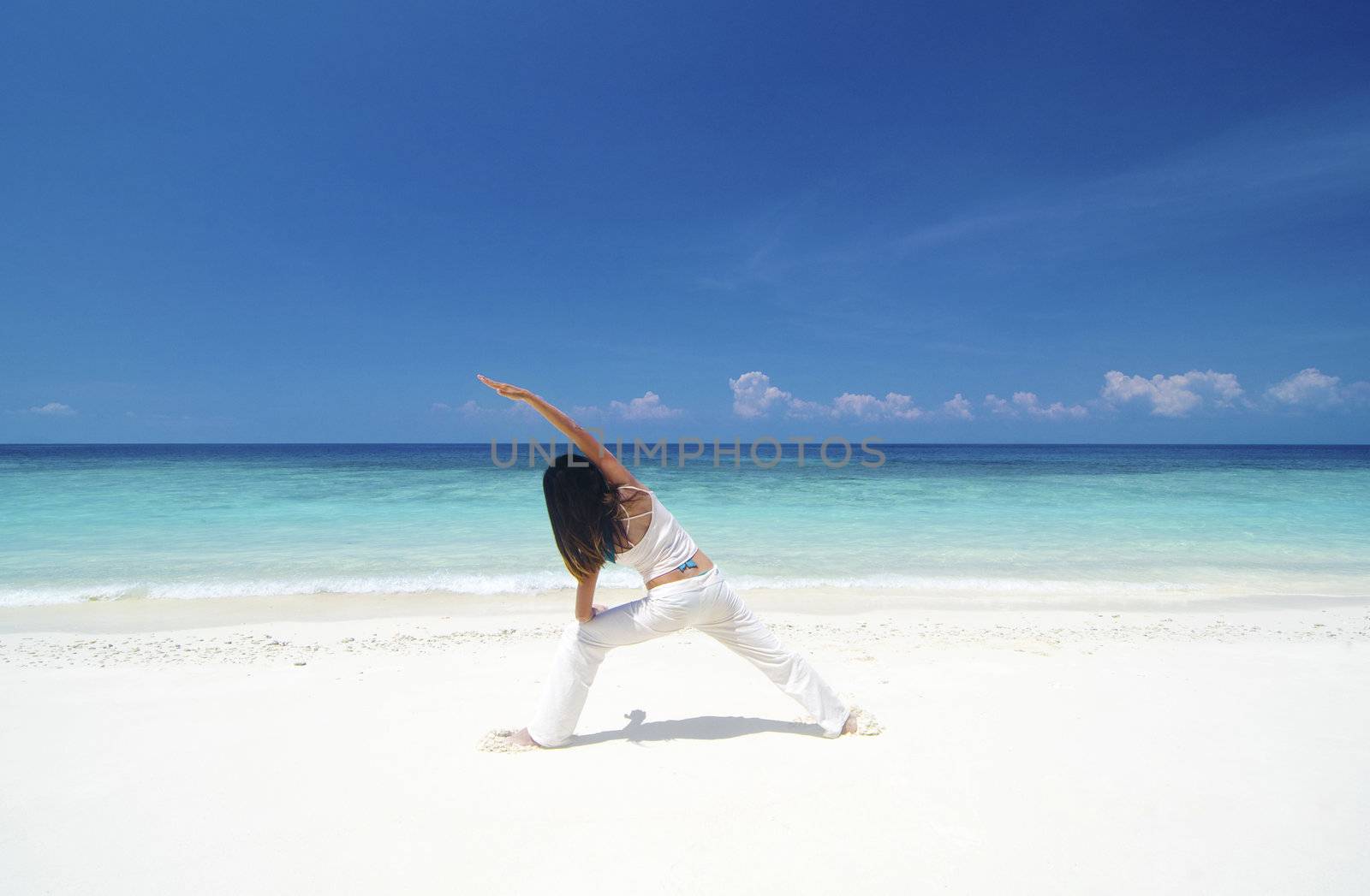 Woman practicing Yoga (Warrior Position) on the beach.