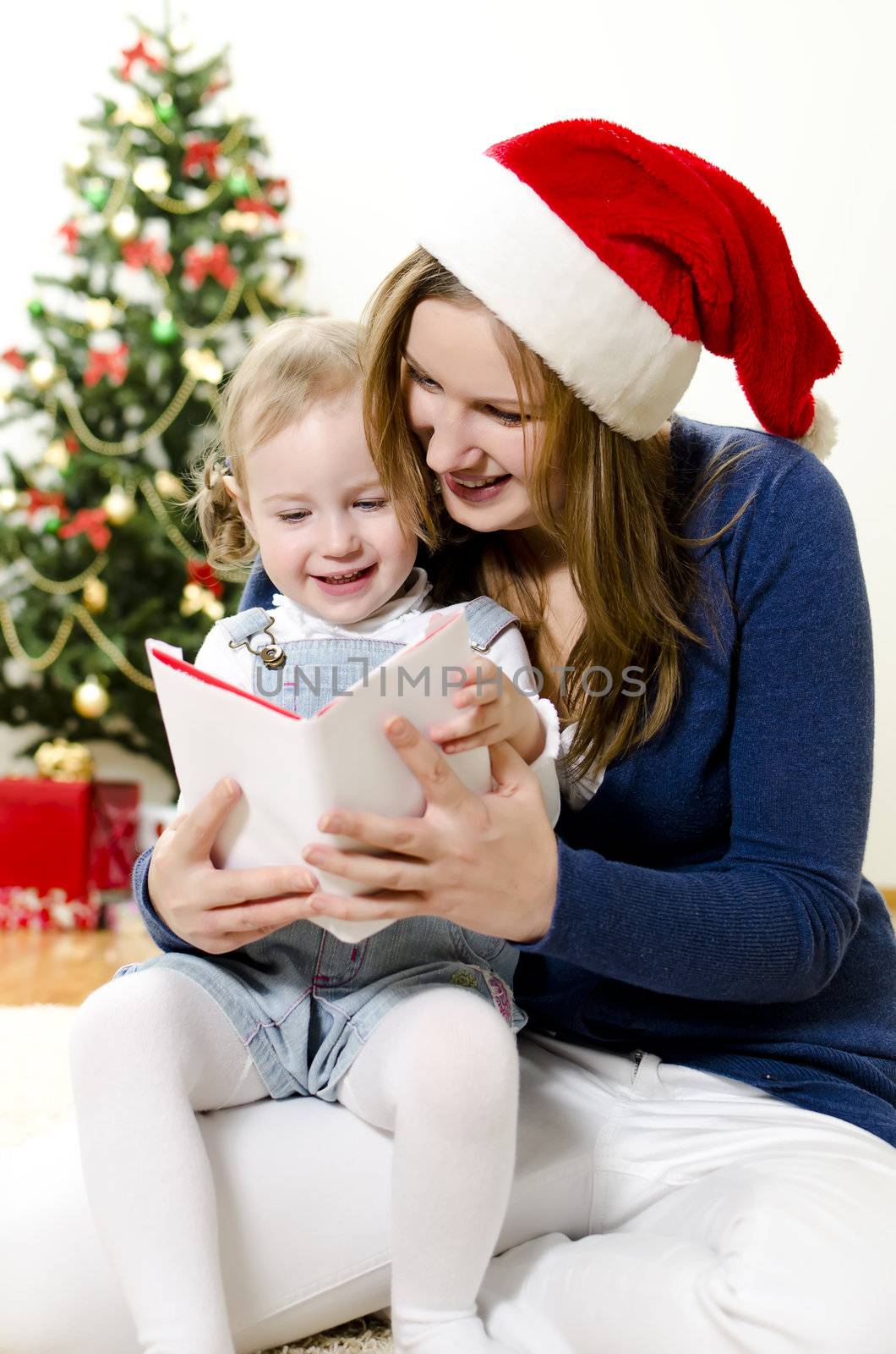 Girl and her mom reading book at Christmas