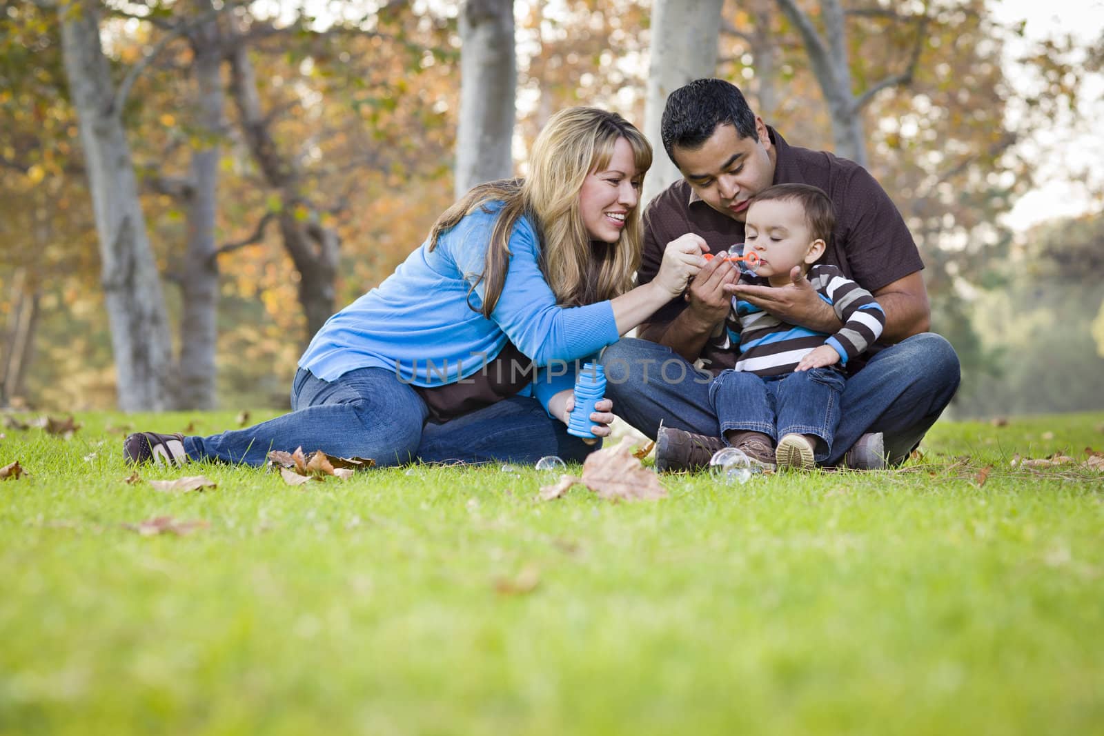 Happy Young Mixed Race Ethnic Family Playing Together with Bubbles In The Park.