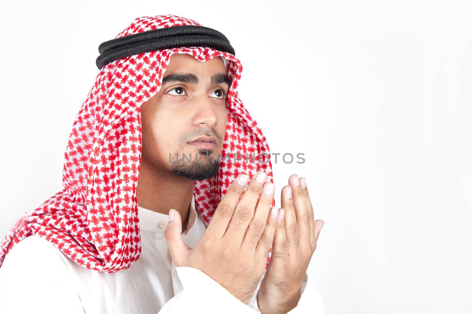 Young arab man of muslim religion praying isolated on white background by haiderazim