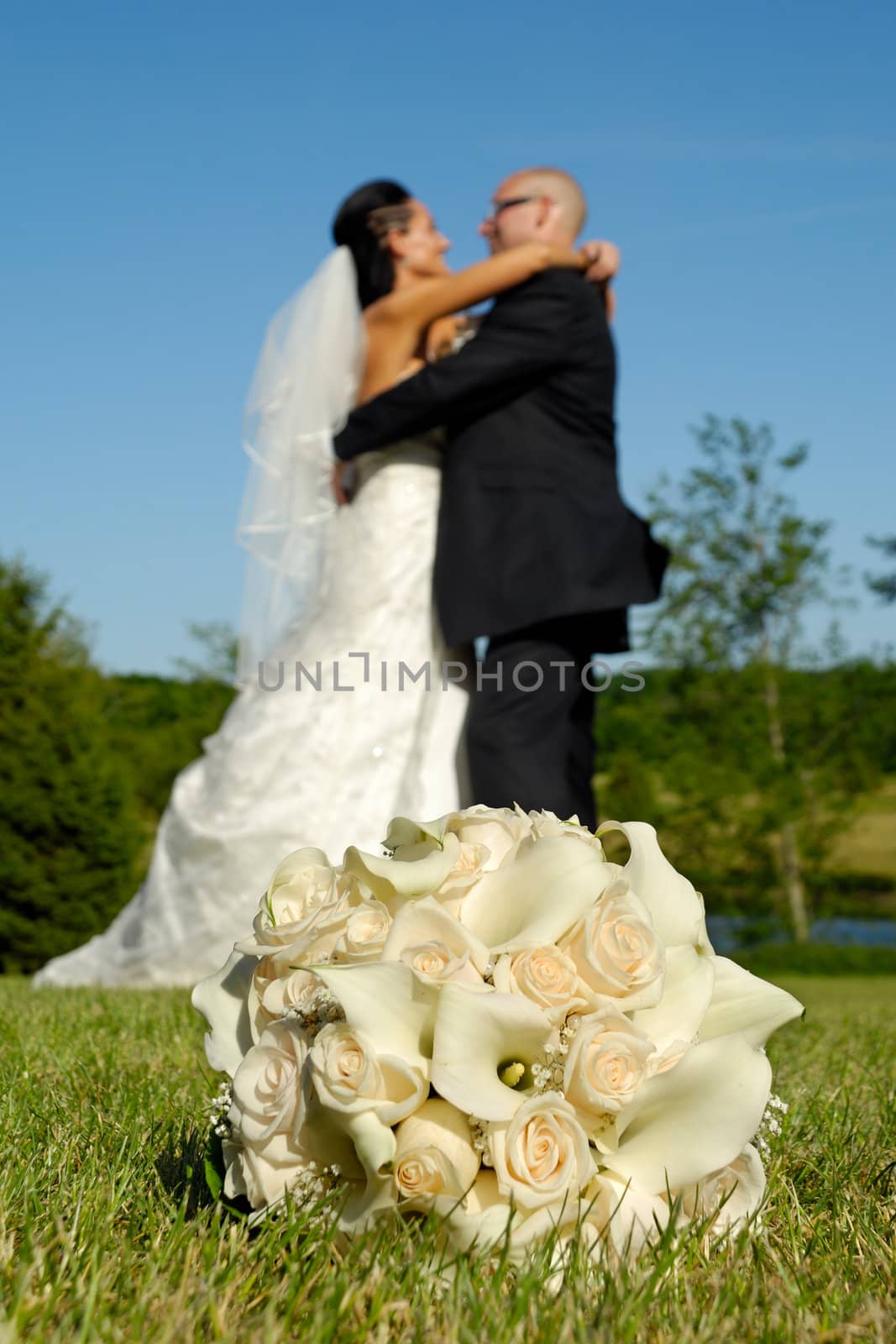 Wedding bouquet in grass in focus and couple in the background 