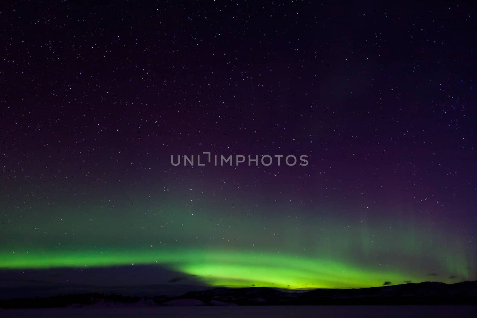 Colorful northern lights (aurora borealis) substorm on dark night sky with myriads of stars.