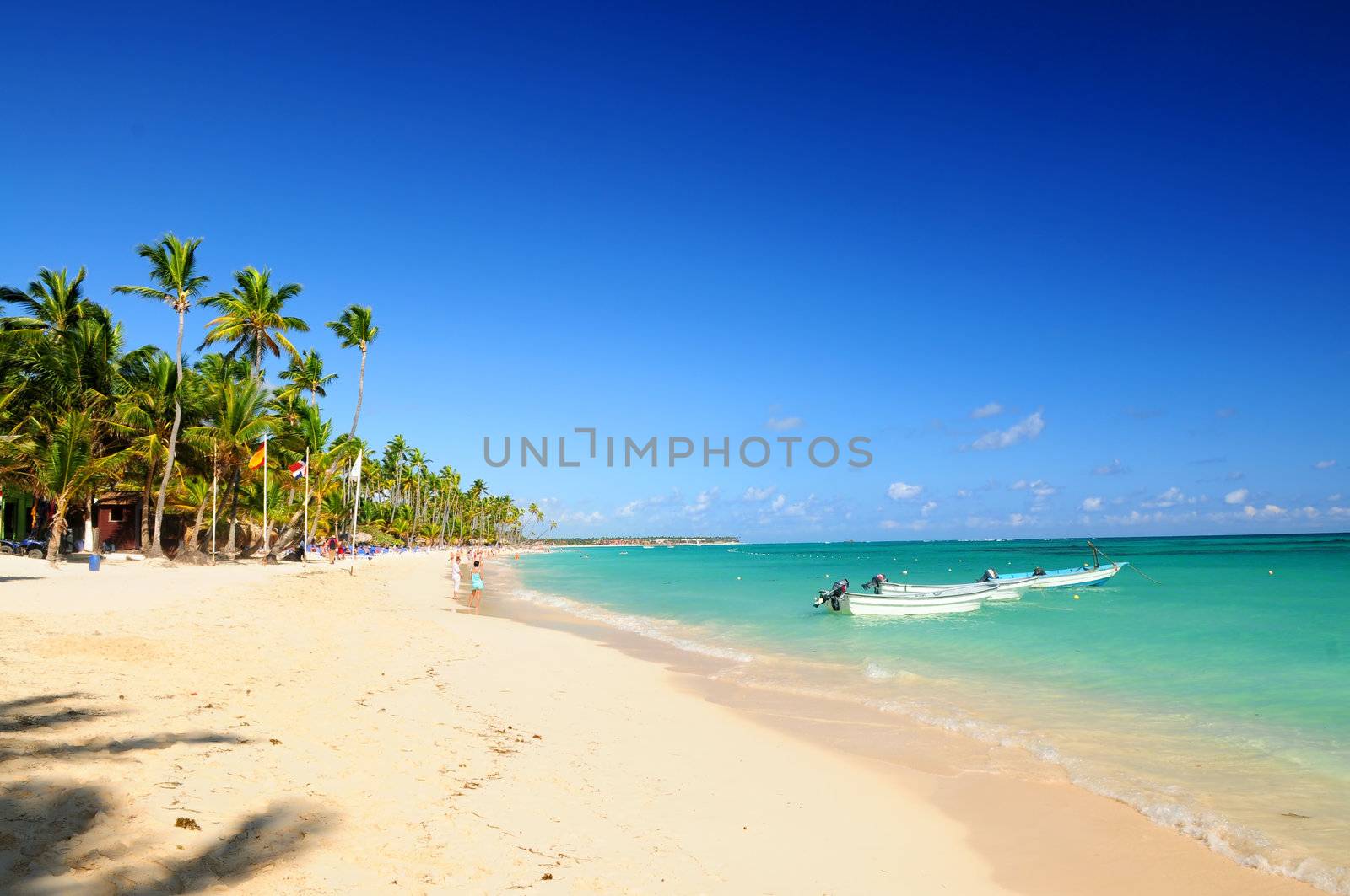 Sandy beach on Caribbean resort and fishing boats at sea